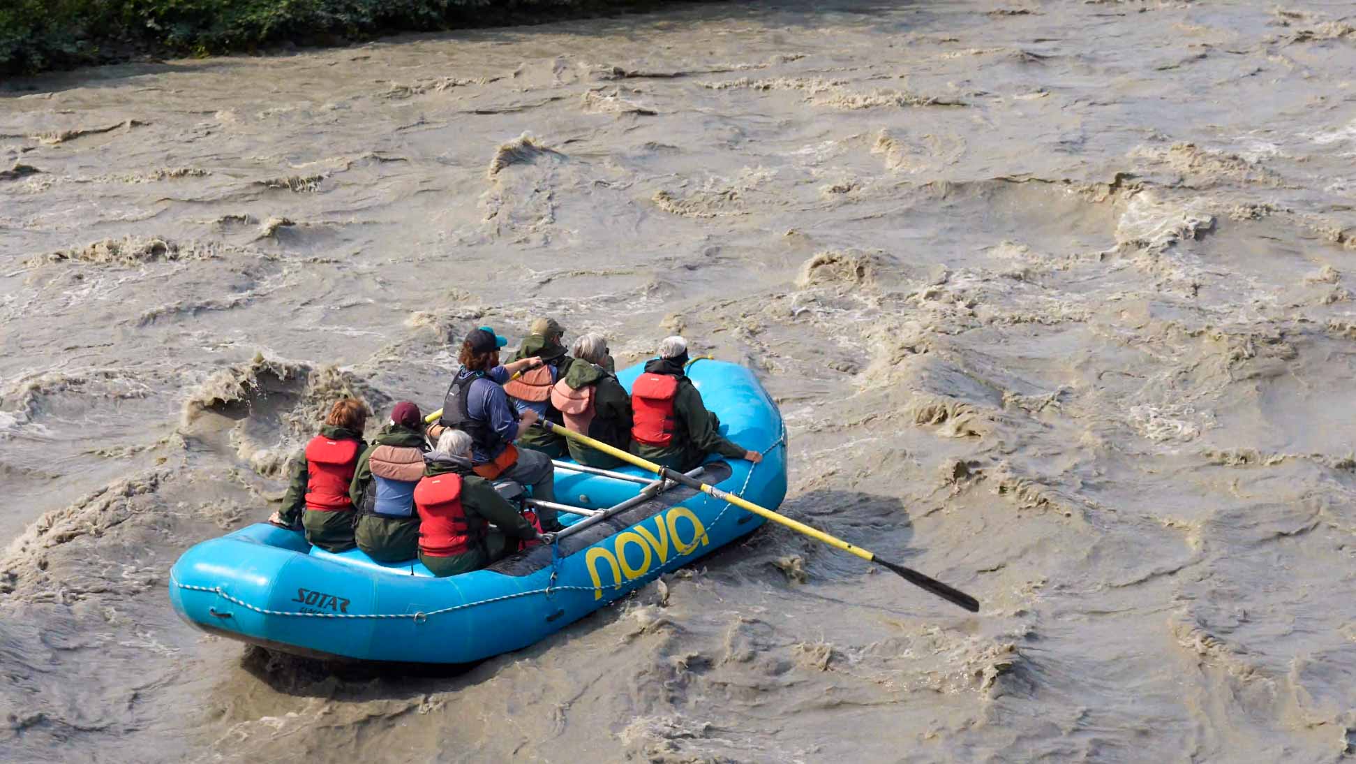 seven people raft down silty whitewater with oar frame raft guide
